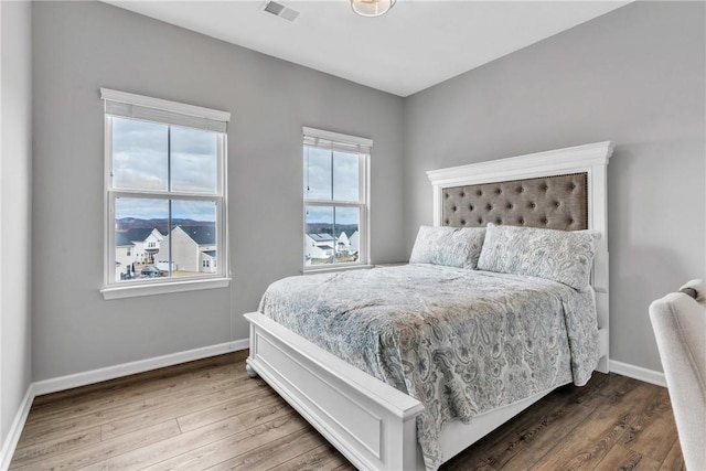 bedroom featuring wood finished floors, visible vents, and baseboards