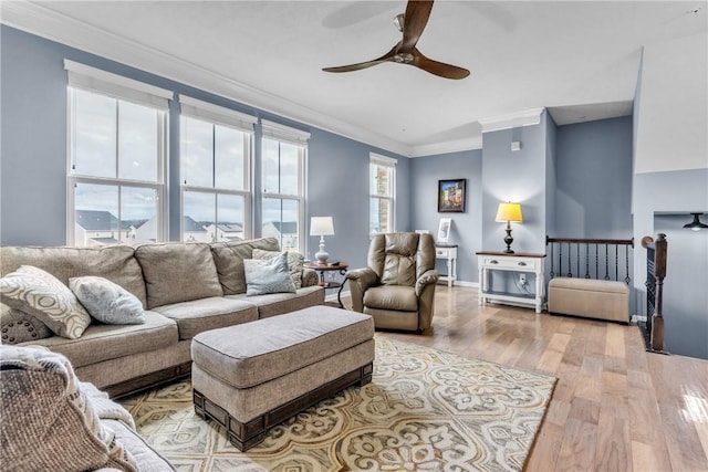 living area featuring light wood finished floors, ceiling fan, ornamental molding, and baseboards