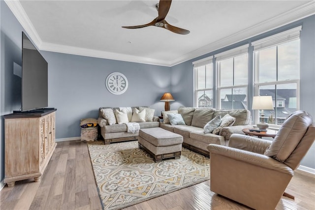 living area featuring light wood finished floors, a ceiling fan, baseboards, and crown molding