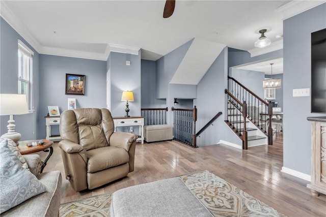 living area featuring a chandelier, ornamental molding, baseboards, and wood finished floors