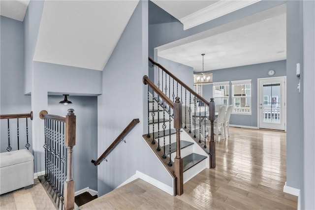 stairs featuring baseboards, a chandelier, and wood finished floors