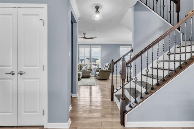 entryway with ornamental molding, stairway, baseboards, and wood finished floors