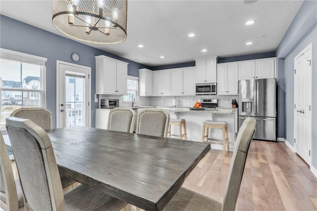 dining room with a chandelier, a toaster, recessed lighting, baseboards, and light wood-type flooring