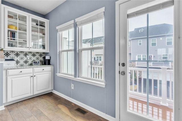 doorway with visible vents, light wood-style flooring, and baseboards