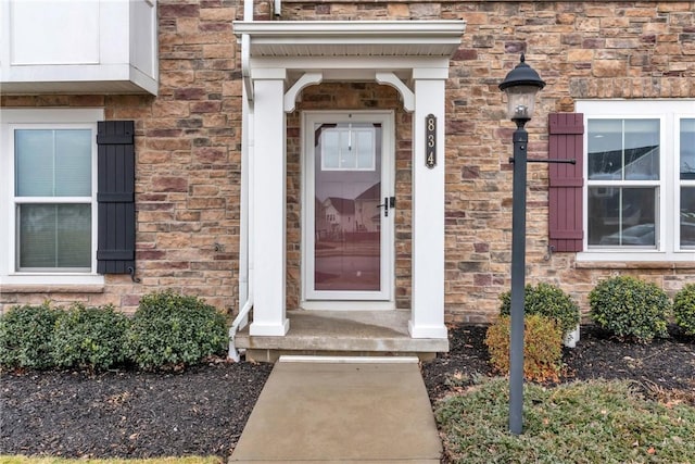 view of exterior entry featuring stone siding and brick siding