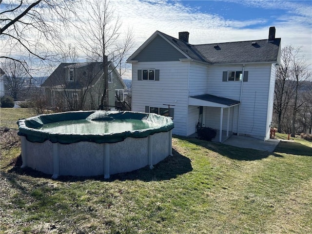 view of swimming pool with a covered pool and a yard