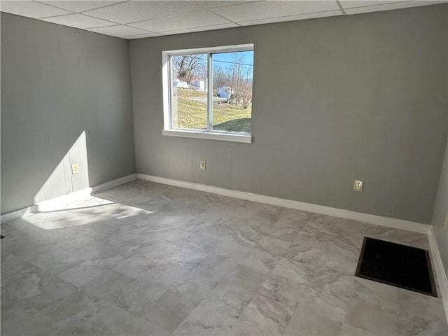 empty room featuring a drop ceiling, visible vents, and baseboards