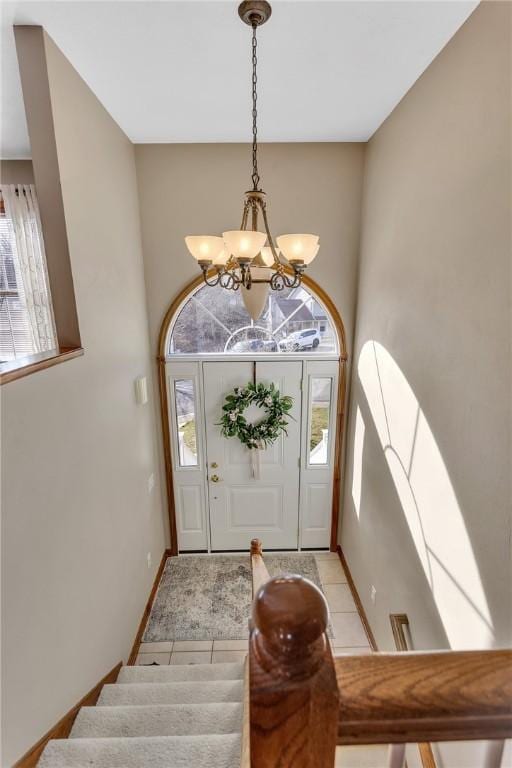 entrance foyer with a wealth of natural light, light tile patterned floors, baseboards, and an inviting chandelier