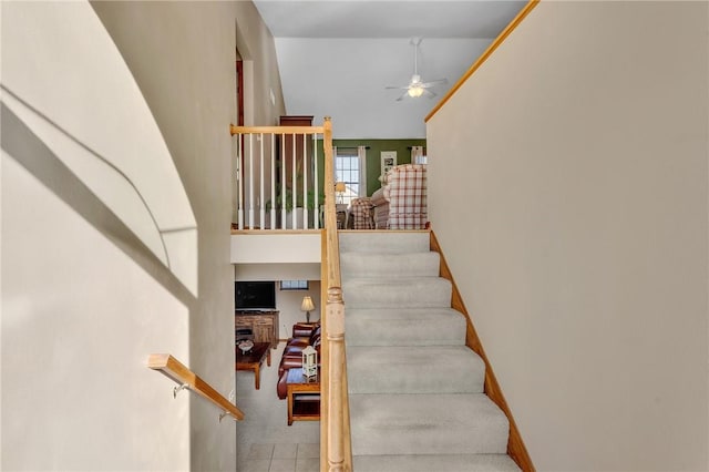 staircase with ceiling fan, high vaulted ceiling, a fireplace, and baseboards