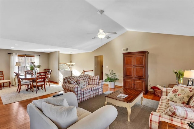 living area featuring high vaulted ceiling, visible vents, wood finished floors, and ceiling fan with notable chandelier