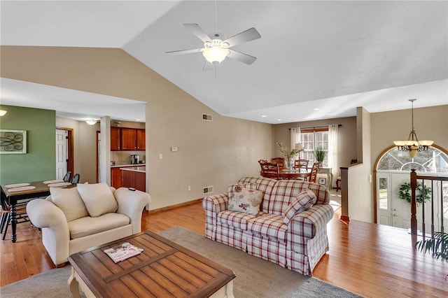 living area with visible vents, light wood-style flooring, and ceiling fan with notable chandelier