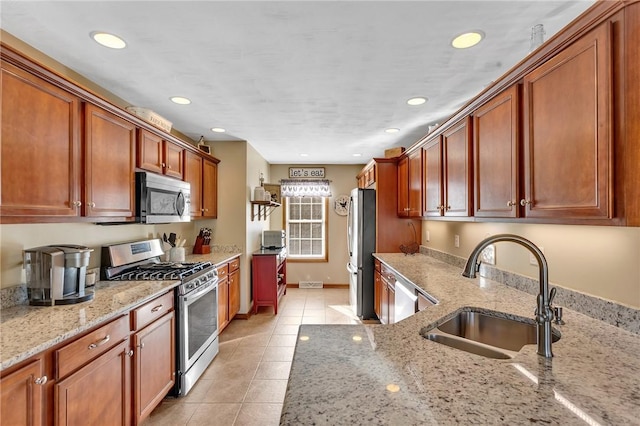 kitchen with light tile patterned floors, recessed lighting, a sink, appliances with stainless steel finishes, and light stone countertops