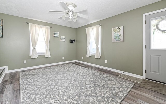 entryway featuring ceiling fan, a textured ceiling, baseboards, and wood finished floors