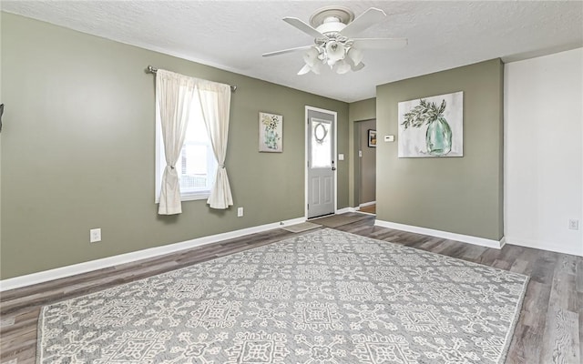 foyer with a textured ceiling, wood finished floors, and baseboards