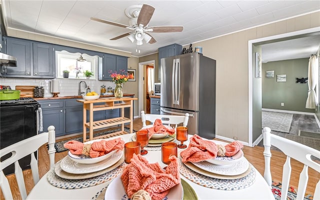 kitchen with butcher block counters, freestanding refrigerator, blue cabinetry, light wood-style floors, and backsplash