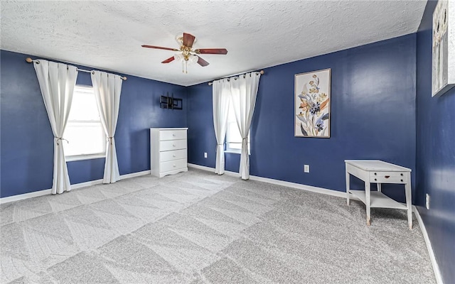 interior space featuring carpet, baseboards, ceiling fan, and a textured ceiling