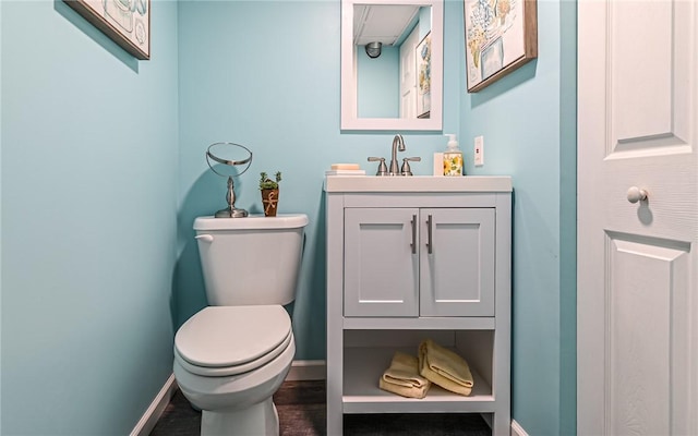 bathroom featuring toilet, baseboards, wood finished floors, and vanity