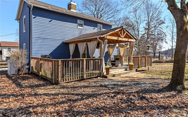 rear view of property with a gazebo, a chimney, and a wooden deck