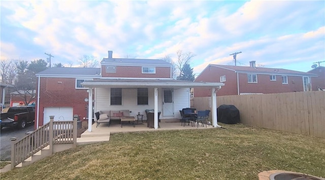 rear view of property featuring a yard, a patio, an outdoor hangout area, fence, and a garage