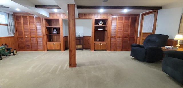 carpeted living room featuring a wainscoted wall, wood walls, and beam ceiling