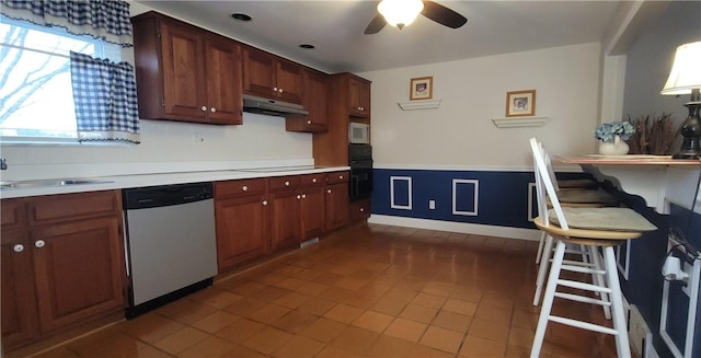 kitchen with under cabinet range hood, black oven, stainless steel dishwasher, light countertops, and stovetop