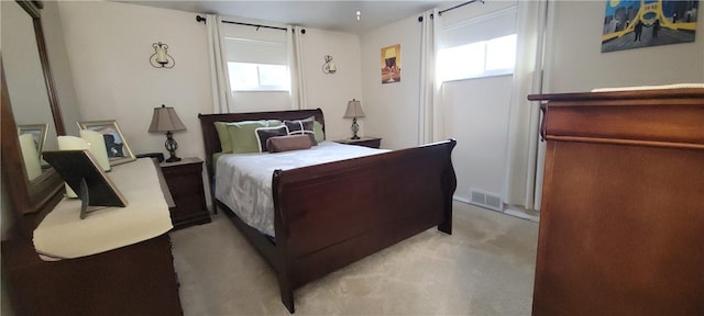 bedroom with light colored carpet, multiple windows, and visible vents