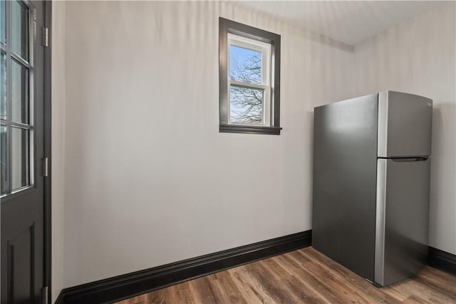 interior space featuring baseboards, wood finished floors, and freestanding refrigerator