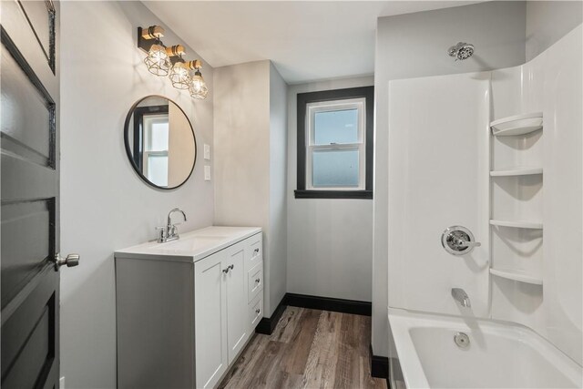 bathroom with bathing tub / shower combination, wood finished floors, vanity, and baseboards