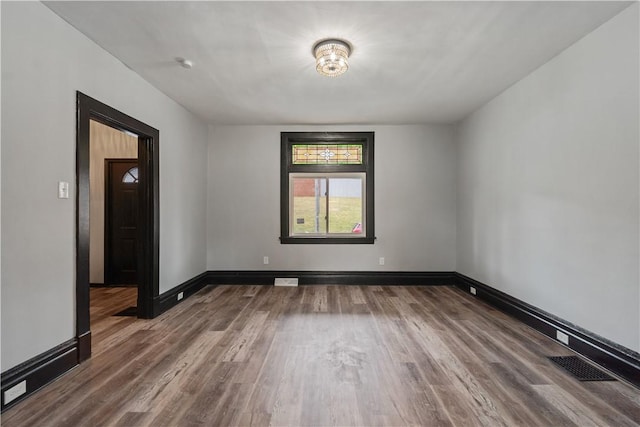 spare room featuring visible vents, baseboards, and wood finished floors