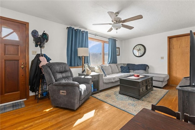 living room with a textured ceiling, wood finished floors, and a ceiling fan