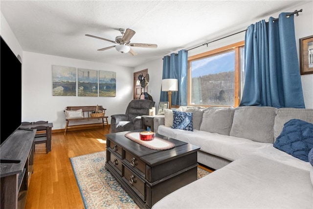 living area with wood-type flooring and ceiling fan