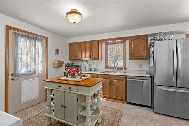 kitchen featuring open shelves, appliances with stainless steel finishes, brown cabinetry, and a sink