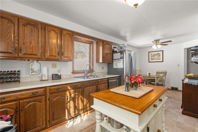 kitchen featuring visible vents, ceiling fan, brown cabinets, stainless steel appliances, and a sink