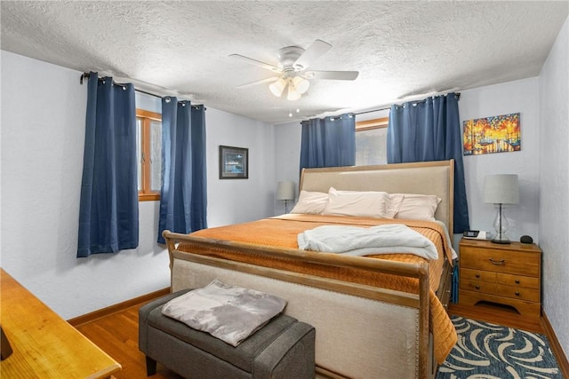 bedroom with baseboards, a textured ceiling, a ceiling fan, and wood finished floors