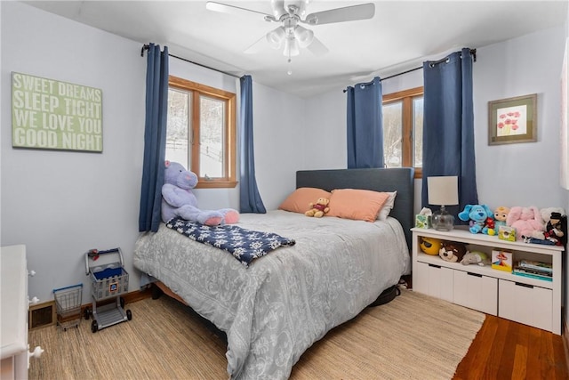 bedroom with ceiling fan, multiple windows, and wood finished floors