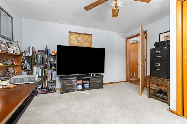 carpeted living room featuring ceiling fan, arched walkways, and baseboards