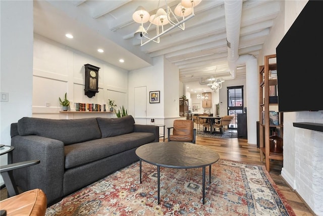 living area with recessed lighting, beam ceiling, a notable chandelier, and wood finished floors