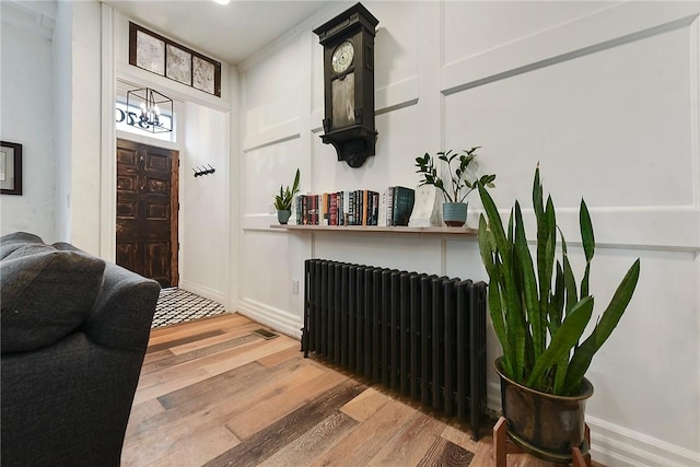 entrance foyer with an inviting chandelier, wood finished floors, and radiator