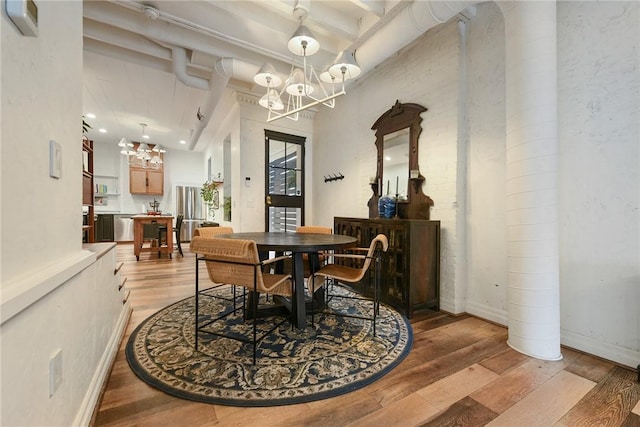 dining room featuring light wood-type flooring, beam ceiling, baseboards, and an inviting chandelier