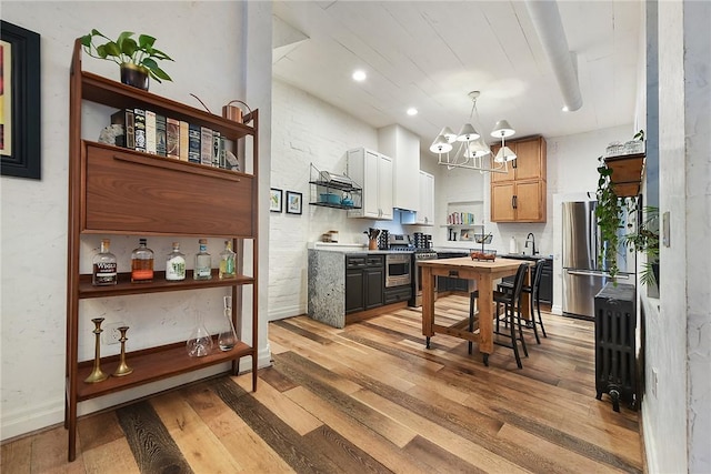 kitchen with light wood finished floors, freestanding refrigerator, a notable chandelier, open shelves, and a sink