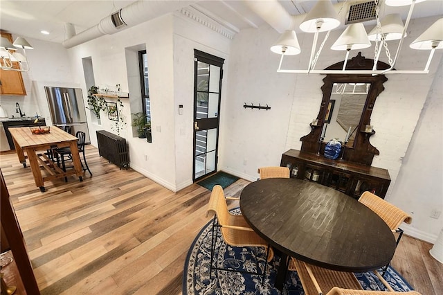 dining area featuring light wood finished floors, visible vents, and baseboards