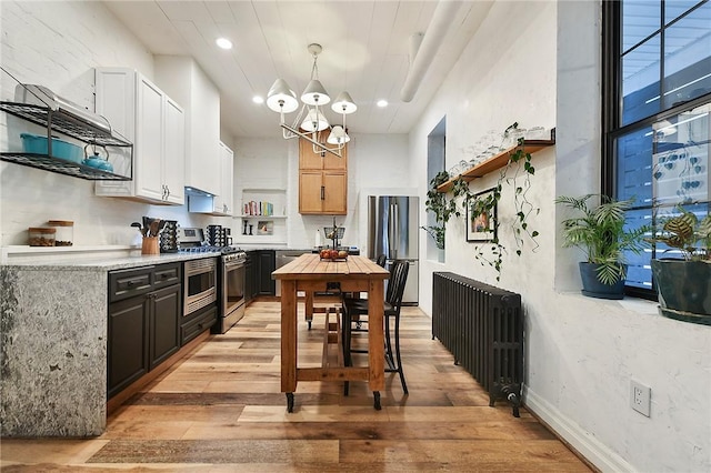 kitchen featuring open shelves, light countertops, radiator heating unit, an inviting chandelier, and appliances with stainless steel finishes