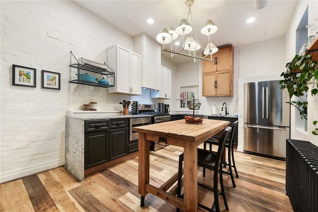 kitchen with brick wall, stainless steel appliances, a sink, and light wood-style flooring