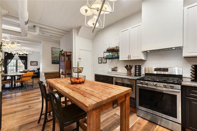 kitchen featuring a notable chandelier, stainless steel appliances, white cabinets, light wood-style floors, and wall chimney exhaust hood