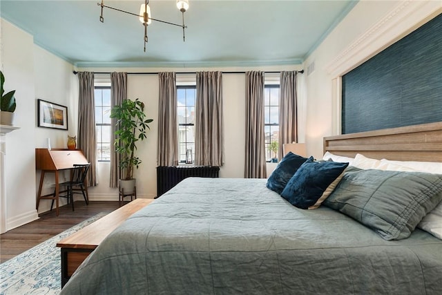 bedroom featuring radiator heating unit, multiple windows, wood finished floors, and crown molding