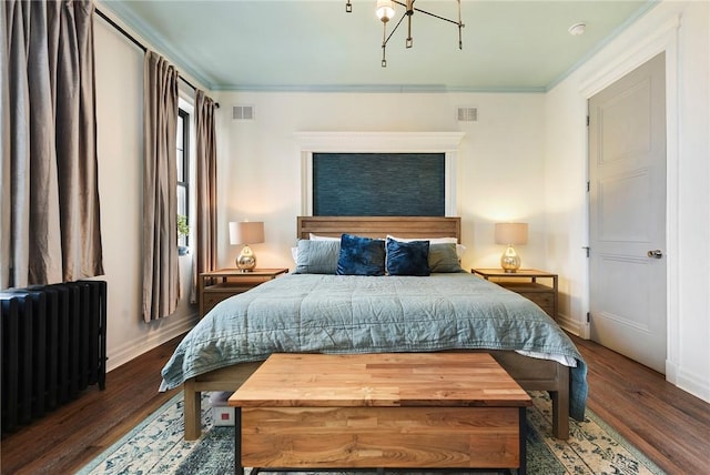 bedroom with radiator, crown molding, baseboards, and wood finished floors