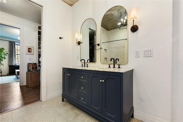 full bathroom with a sink, baseboards, and double vanity