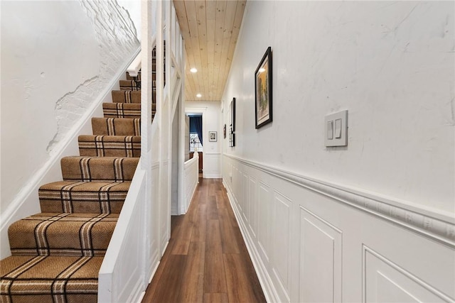 hallway with recessed lighting, a decorative wall, dark wood-type flooring, stairs, and wainscoting