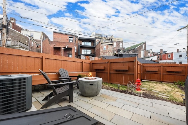 view of patio featuring an outdoor fire pit, central AC, and a fenced backyard