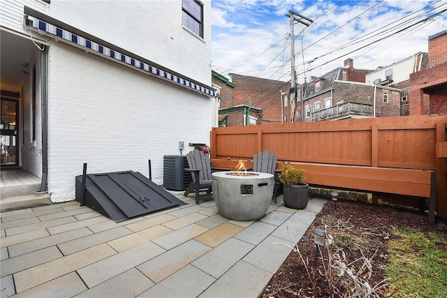 view of patio with an outdoor fire pit, fence, and central air condition unit